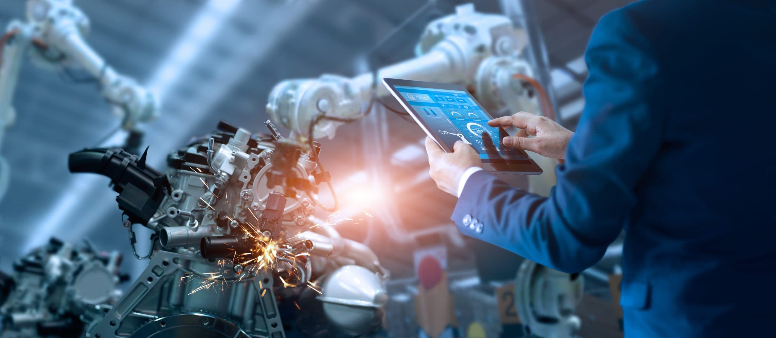 A manufacturing executive in a factory monitoring network security on a tablet device.