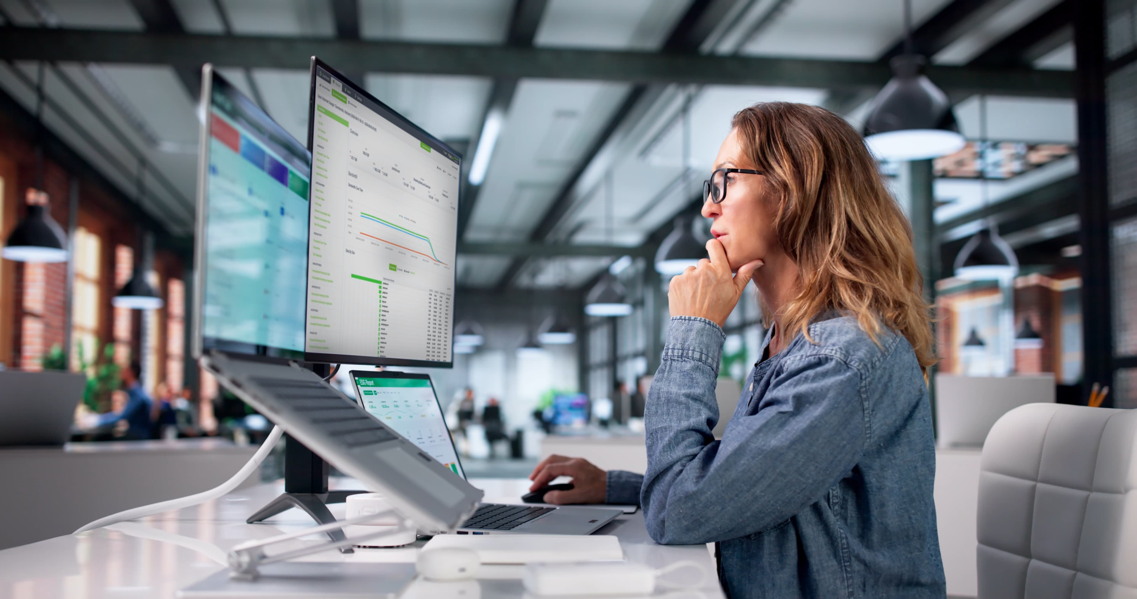 Woman sitting in office lookign at monitor featuring Fastvue Reporter for Business